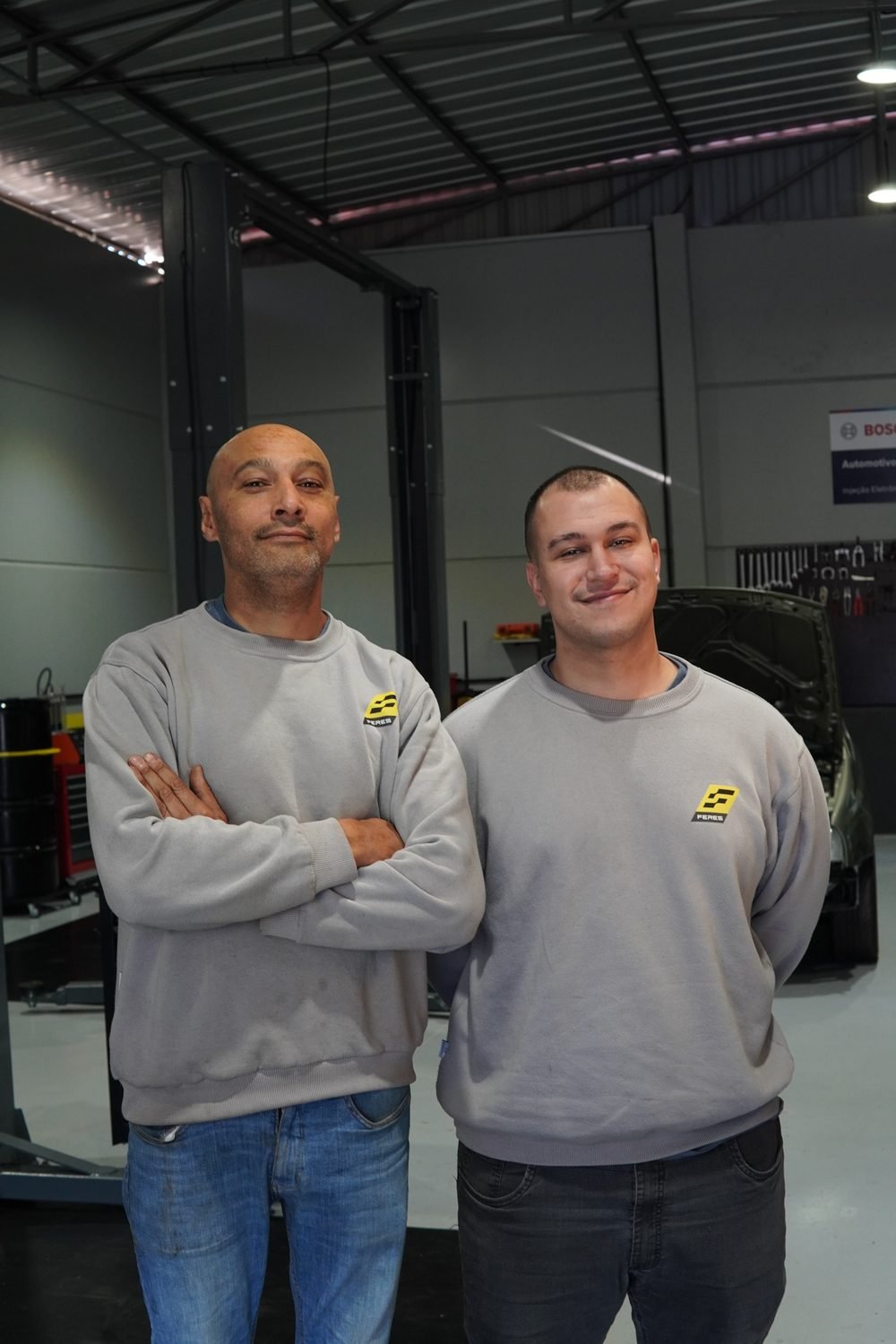 Mecânico da Feres apoiado no vidro de um veículo, uniforme com logo Feres no peito